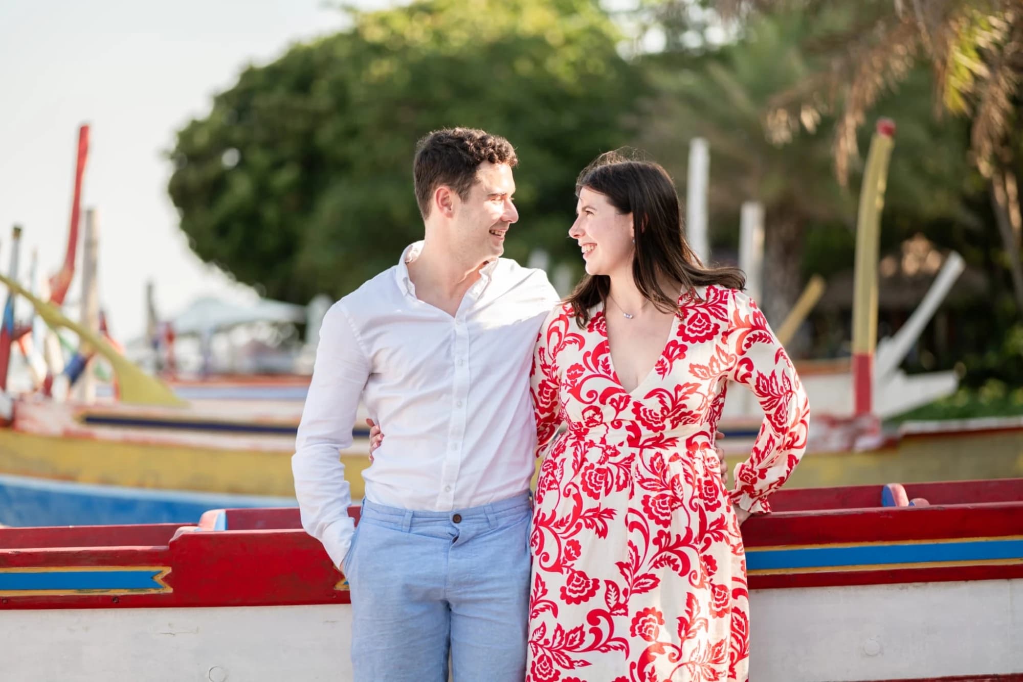 Bríd and Barry smiling at each other beside colourful boats